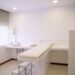 Testimonio Gestión centro de uñas Lluisa Albiol Muñoz 2 Minimalist white clinic room with examination table and furniture.